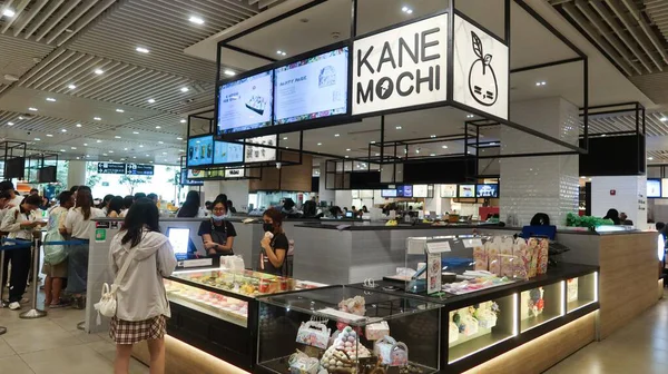 Changi Airport, Singapore- 16 Aug 2025: a lady is buying food in the food court counter offering sweets and confectionery, a shop called Kane Mochi
