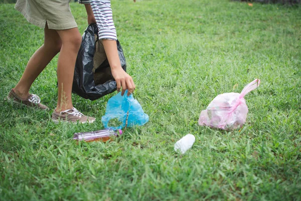 Human hand picking up plastic into bin bag on park ,volunteer concept