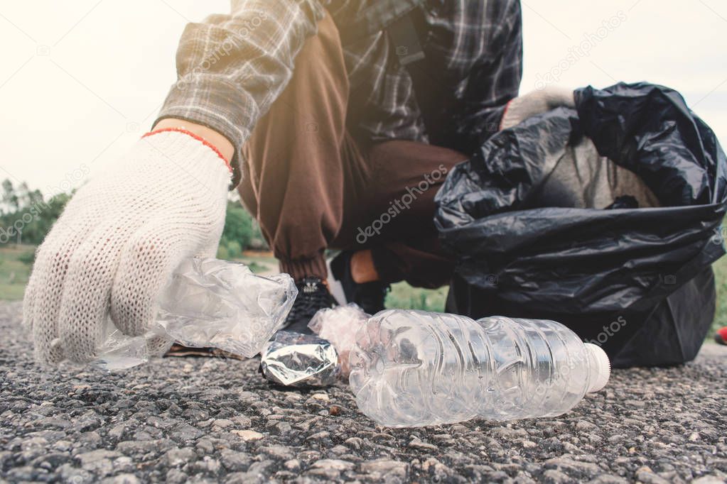 Human hand picking up empty of bottle plastic on park ,volunteer concept