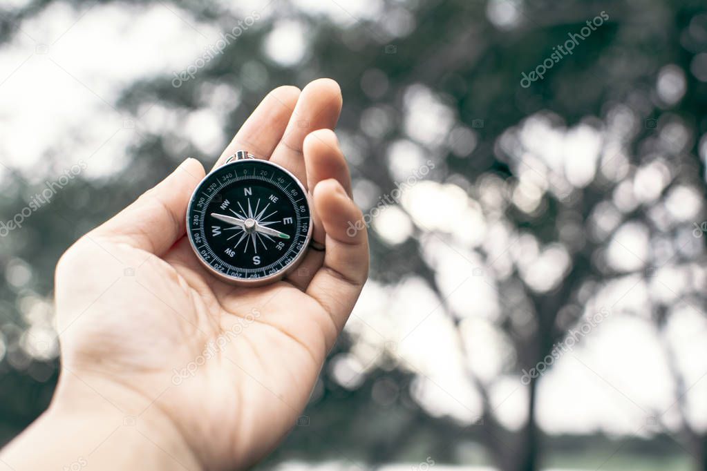 Hand holding compass in the nature, color vintage style