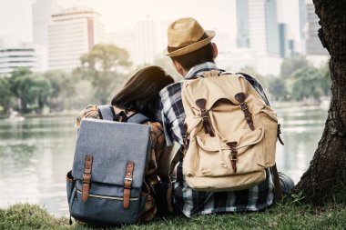 Park arka plan, tatil kavramı yolculuğa ağacın altında oturan hipster çift backpacking .