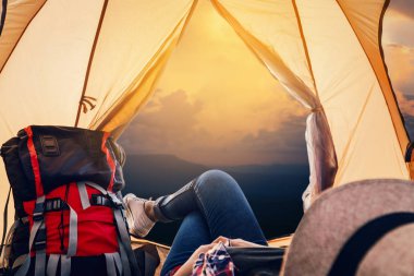 Hipster kadın dinlenme ve tatile gündoğumu çadır piknik içinde uyuyan güzel doğa arka plan, seyahat ve mutlu zaman kavramı yolculuk görüntülemek.