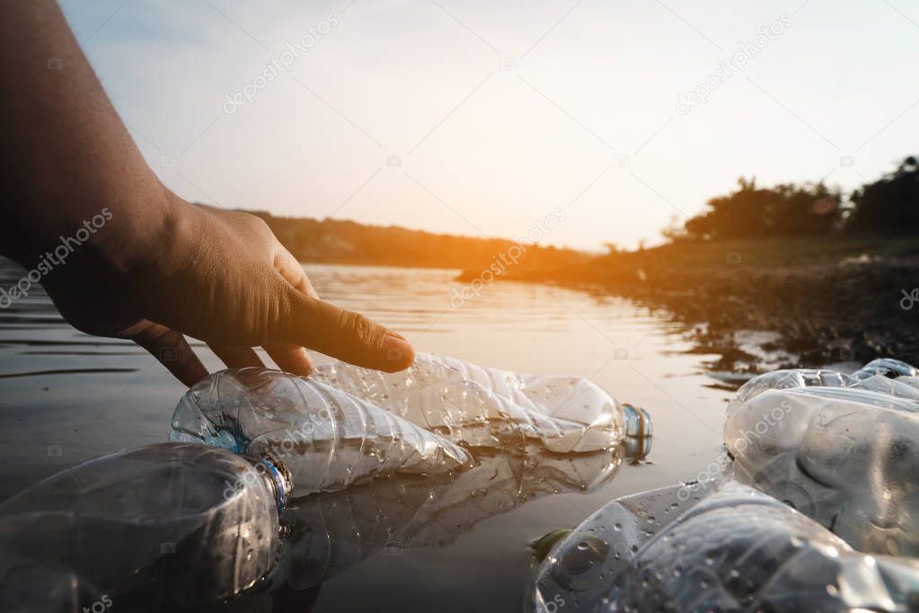 The volunteer picking up a bottle plastic in the river , protect environment from a pollution concept.