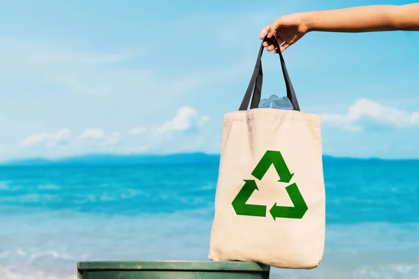 The volunteer holding a plastic bag in to a bin and the sea background ,recycling and protect environment from a pollution concept.