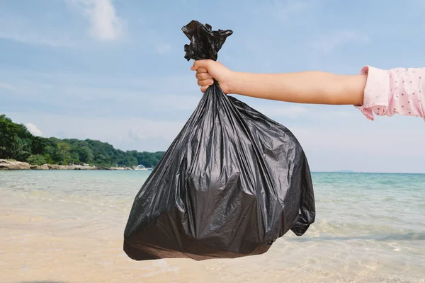 Hand hält Plastiktüte und das Meer Hintergrund — Stockfoto