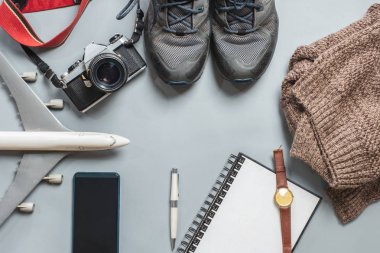 Vintage fotoğraf makinesi, uçak, Ayakkabı, defter, ceket, gri arka plan üzerinde seyahat aksesuarları tatilde. Üstten görünüm kopya alanı