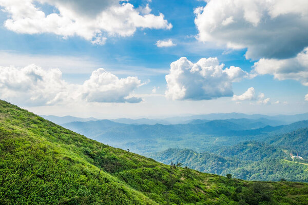 Green mountain peak slope and bright sky