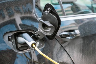 Elektrikli modern otomobil kablo güç kaynağıyla kenarındaki istasyonda takılı şarj