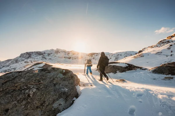 つは輝く日没で雪のフィールドでピーク山へハイキング登山家します — ストック写真