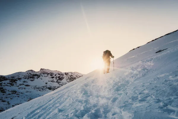 夕日に輝く冬のピークの山に登る登山家男 — ストック写真