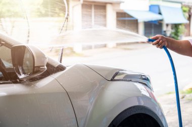 El yıkama araba beyaz araba üzerinde basınç su hortum ile