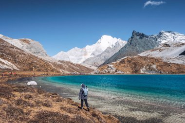 Young women trekking on top of Milk Lake in peak valley at Yading nature reserve clipart