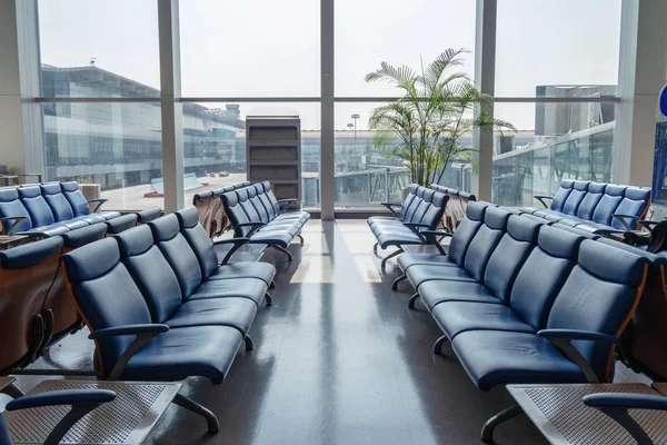 Рядки стільця зі скляними вікнами світяться в терміналі в аеропорту — стокове фото