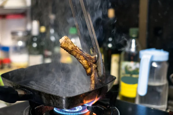 Pinzas de cocina sujeción filete de ternera madura en la sartén —  Fotos de Stock