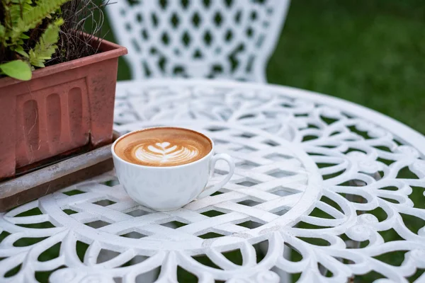 Kaffee heißer Latte mit Blütenform in weißer Tasse auf Retro-Tisch — Stockfoto