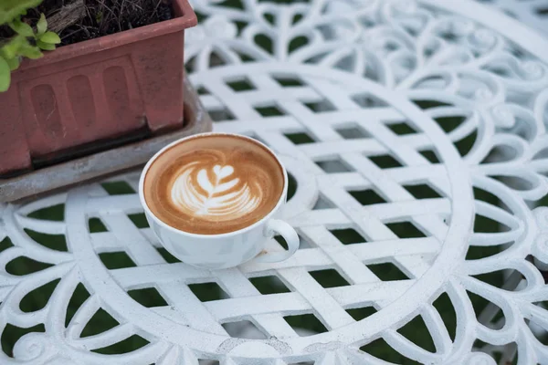 Kaffee heißer Latte mit Blütenform in weißer Tasse auf Retro-Tisch — Stockfoto