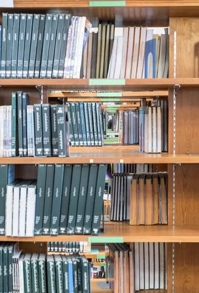 Muitos tipo de livro empilhados na prateleira de madeira — Fotografia de Stock