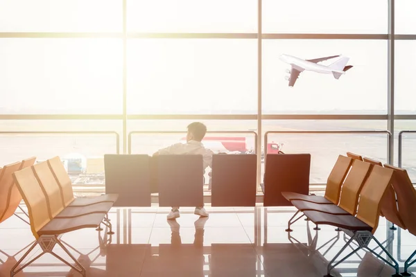 Человек пассажир ждет на сиденье в терминале ворот с самолетом — стоковое фото