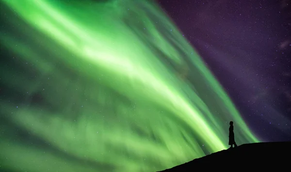 Silhouette Frau steht auf Klippe mit Polarlichtern tanzen — Stockfoto