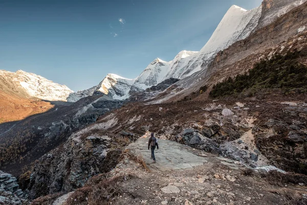 Mann Backpacker zu Fuß zu Klippe mit Schnee-Gebirge — Stockfoto