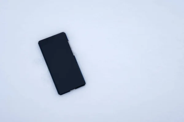 Desligue o smartphone de exibição em branco caindo na neve — Fotografia de Stock