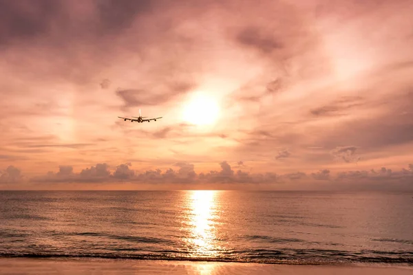 Avión volando a la luz del sol arco en el mar por la noche — Foto de Stock