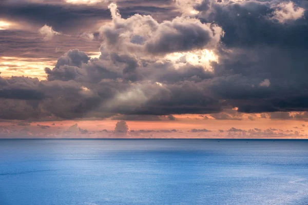 Tormenta oscura nublada con rayo de luz solar en el mar azul por la noche — Foto de Stock