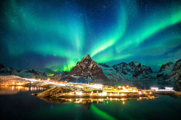 Aurora borealis over mountains in fishing village