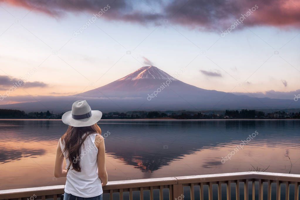 Young asian woman standing on wood balcony looking Fuji-san moun