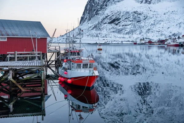 Barco de pesca ancorado no cais com aldeia vermelha na ilha Lofoten — Fotografia de Stock
