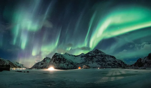 Aurora boreal o auroras boreales sobre la montaña de nieve en la costa —  Fotos de Stock