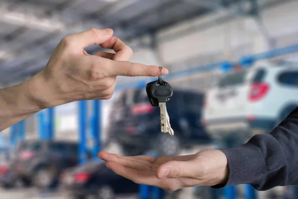Hand handing over car keys with finger and hand receiving on gar