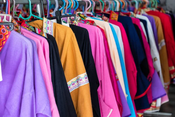 Красочная одежда из хлопчатобумажной ткани висит на рельсах в магазине — стоковое фото