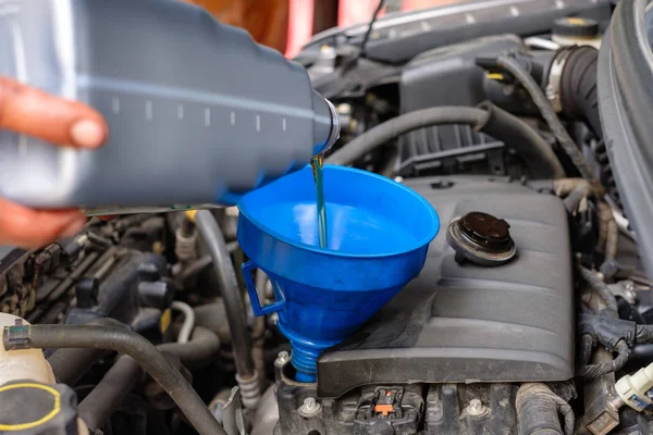 Cambio mecánico de mano vertiendo aceite de motor sintético nuevo a la cacerola i — Foto de Stock