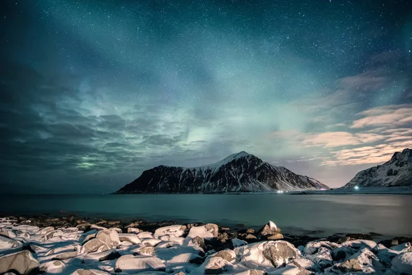 Aurora boreal con estrellas sobre cordillera con costa nevada —  Fotos de Stock