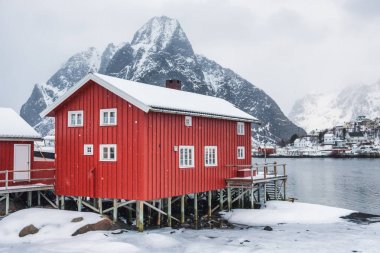 Lofoten kıyı şeridinde vadide kırmızı evde kar yağışı