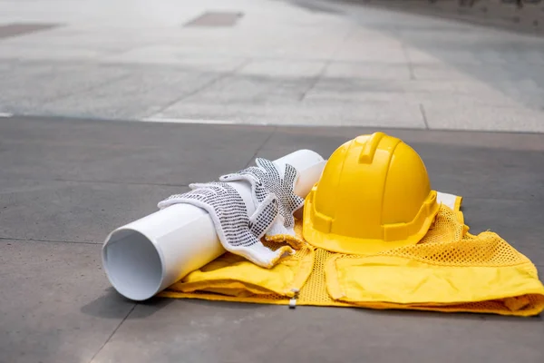 Capacete de segurança amarelo com luva, modelo no colete no chão — Fotografia de Stock