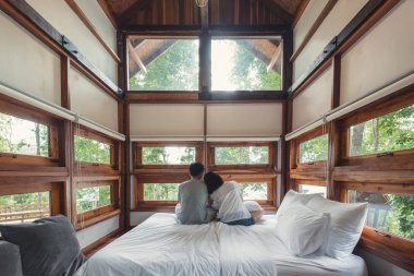 Sevgili çiftler ahşap odada beyaz yatakta rahatlatıcı