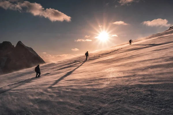 Alpinistów wspinaczka w zamieć na Snowy wzgórzu o zachodzie słońca — Zdjęcie stockowe