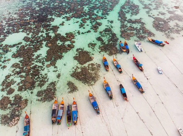 Uzun kuyruklu ahşap botlar mercan kayalıklarıyla kıyı şeridine demir atıyor.