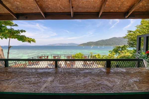 Ağaçlı, tropikal denizde çatısı olan ahşap bir masa.