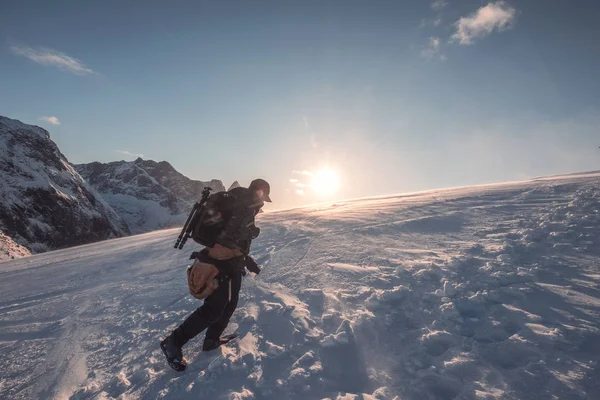 太陽の下で青空と雪山に登る男性写真家 — ストック写真