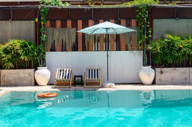 Yüzme havuzunda şemsiye ile ahşap şezlong