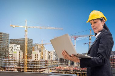 Bina yapısı ve mavi gökyüzü üzerinde dizüstü bilgisayar kullanan kadın mühendis