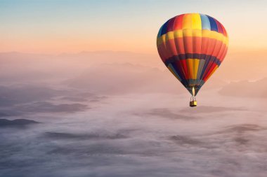 Sis ve manzara ile havada uçan renkli sıcak hava balonu 