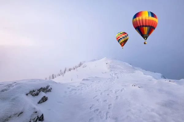 Balões de ar quente coloridos voando na colina de neve com nevasca — Fotografia de Stock