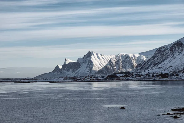 Kıyılarda Norveç köyü ile kar dağ sırası manzarası — Stok fotoğraf