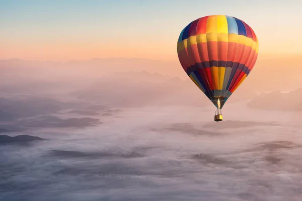 Farverig varmluftsballon flyver i luften med tåge og natur - Stock-foto