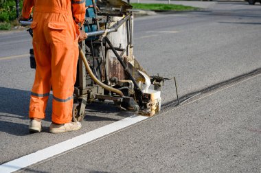 Üniforma giyen işçi pai ile yolda beyaz çizgi yapıyor