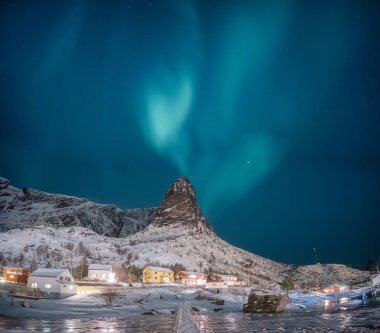 Northern lights on snow mountain with fishing village at Lofoten clipart